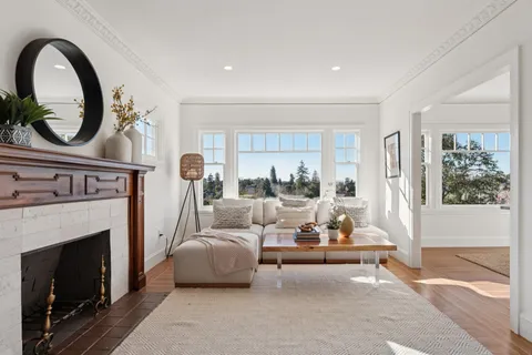 a living room with furniture a fireplace and a floor to ceiling window