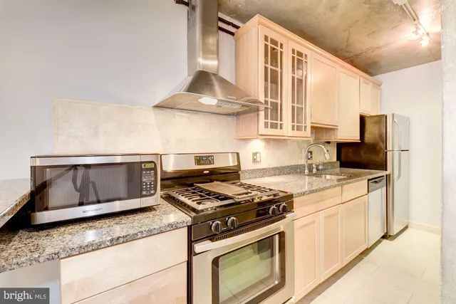 a kitchen with stainless steel appliances granite countertop a stove a sink and a microwave