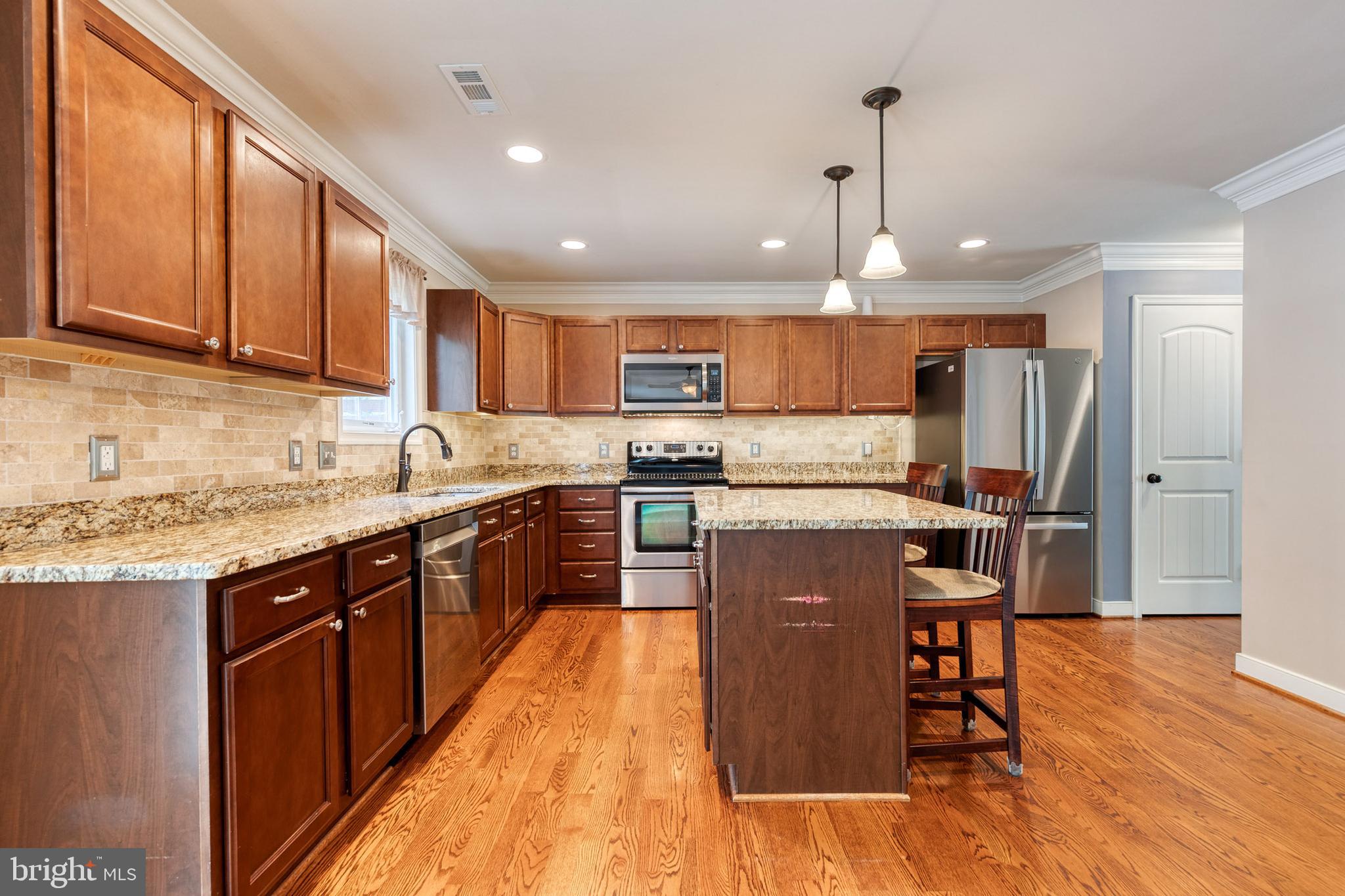 768 Stevenson Road Severn, MD 21144 - Photo 11 of 41 a kitchen with stainless steel appliances granite countertop wooden cabinets a refrigerator a stove a sink and a chairs