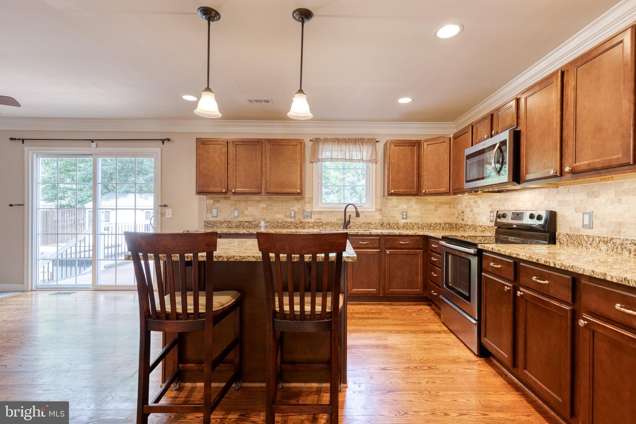 768 Stevenson Road Severn, MD 21144 - Photo 13 of 41 a kitchen with stainless steel appliances granite countertop wooden floor a sink a stove a dining table and chairs
