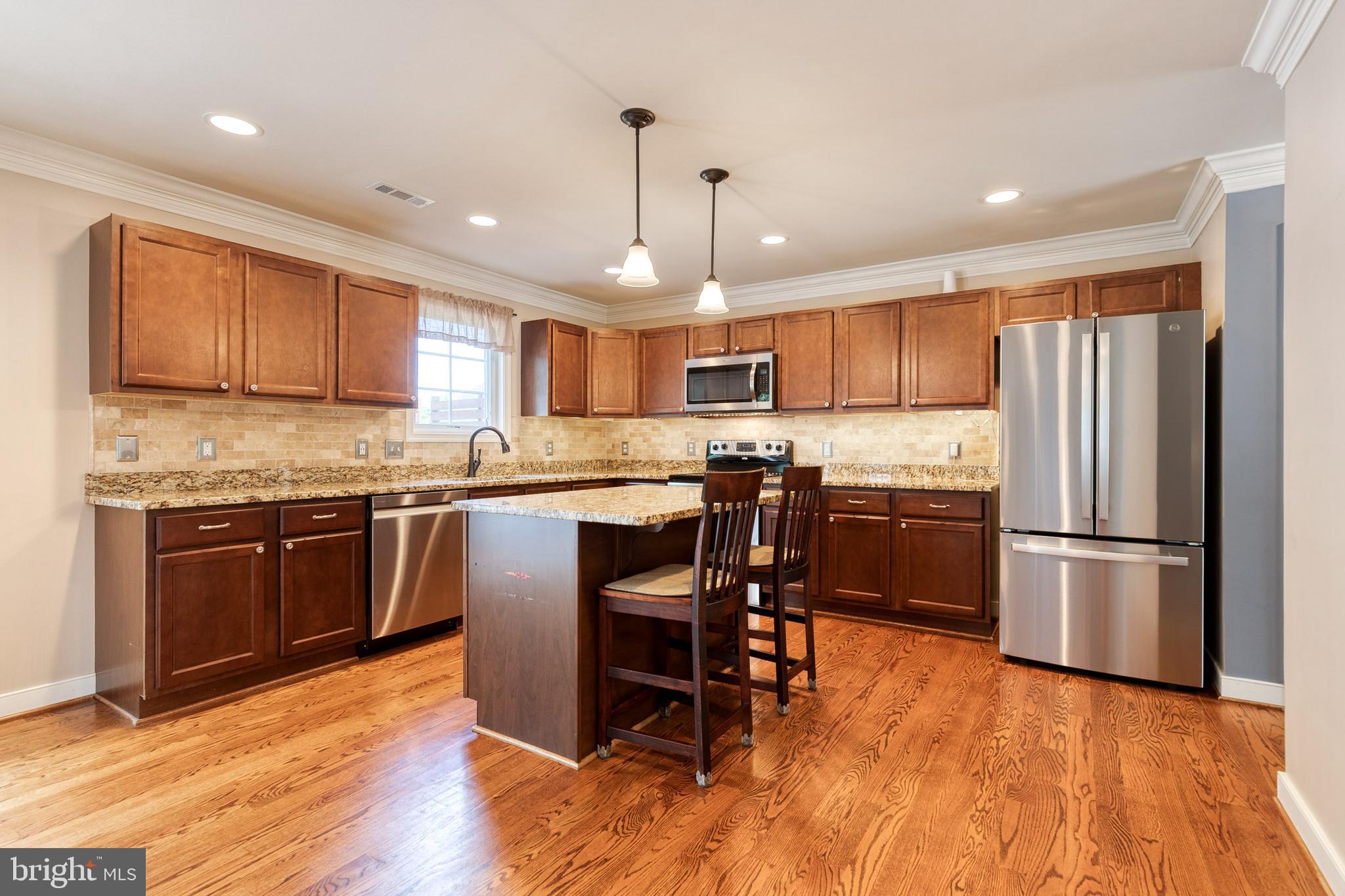 768 Stevenson Road Severn, MD 21144 - Photo 7 of 41 a kitchen with kitchen island granite countertop wooden floors stainless steel appliances and a island