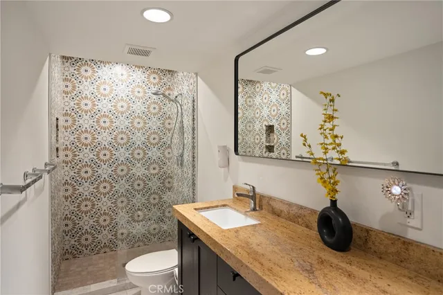 a bathroom with a granite countertop sink a toilet and shower