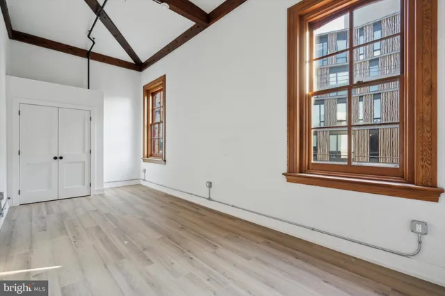 a view of an empty room with a window and wooden floor