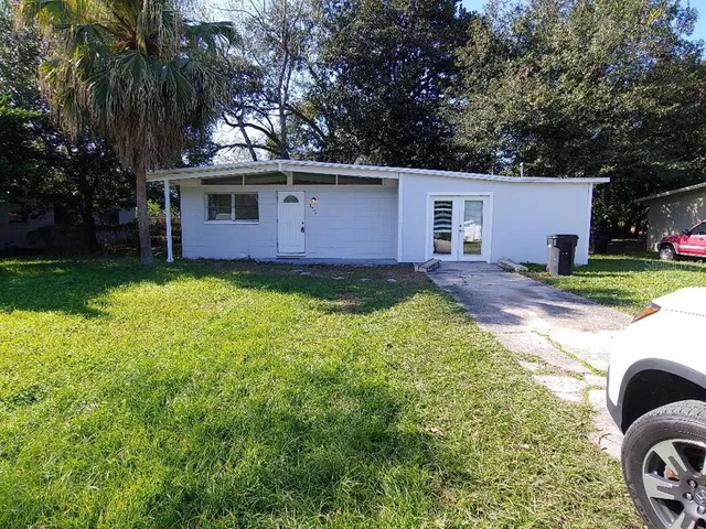 a view of a house with a yard and a large tree