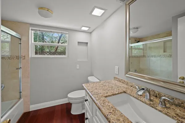 an empty room with wooden floor chandelier fan and windows