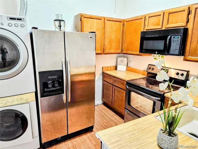 a kitchen with stainless steel appliances granite countertop a refrigerator a stove and a sink with wooden floor