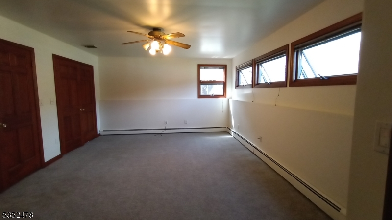 83 Lakeside Drive Vernon, NJ 07461 - Photo 9 of 34 an empty room with windows and chandelier fan
