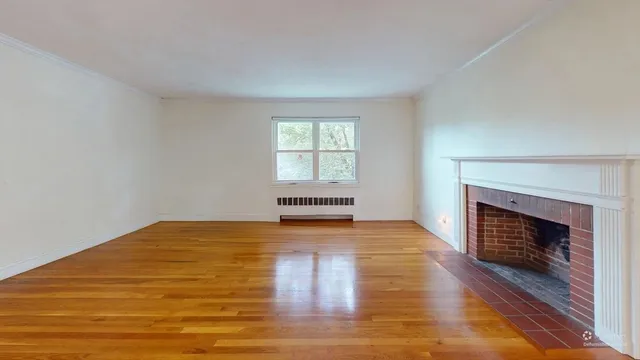 a view of empty room with wooden floor and fireplace