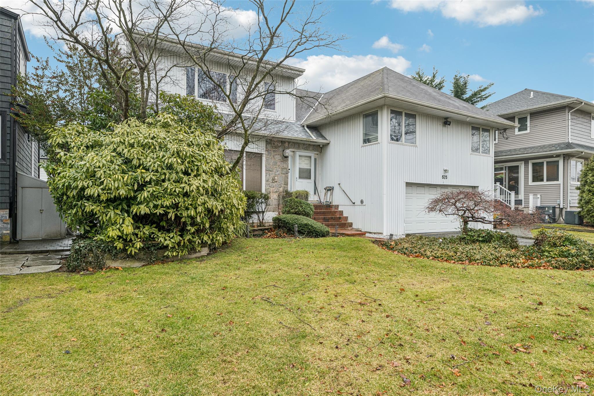 575 Rica Lane Woodmere, NY 11598 - Photo 2 of 24 View of front of home with a front yard, a garage, and roof with shingles