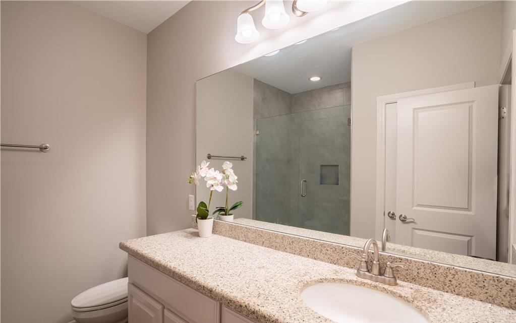 14117 Boykin Creek Road McAllen, TX 78504 - Photo 10 of 19 a bathroom with a granite countertop sink a toilet and a mirror