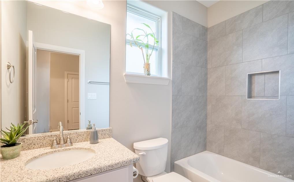 14117 Boykin Creek Road McAllen, TX 78504 - Photo 16 of 19 a bathroom with a granite countertop toilet a sink and a mirror