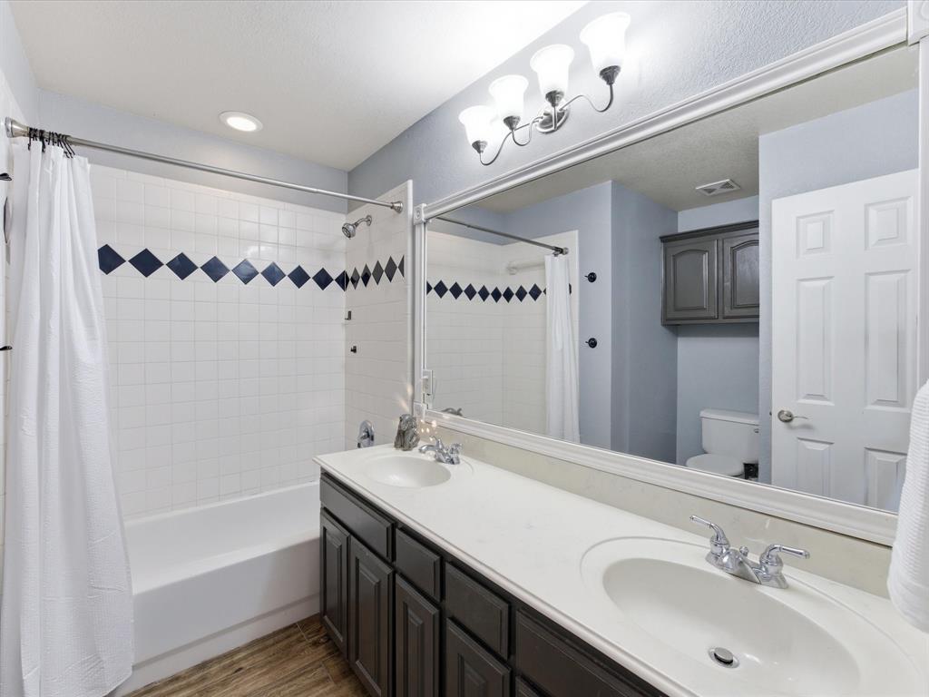 10000 Fireside Lane Forney, TX 75126 - Photo 15 of 40 Bathroom with double vanity, shower / bathtub combination with curtain, and dark wood finished floors