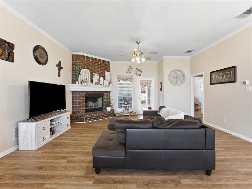 10000 Fireside Lane Forney, TX 75126 - Photo 20 of 40 Living area featuring a ceiling fan, light wood finished floors, crown molding, and a brick fireplace