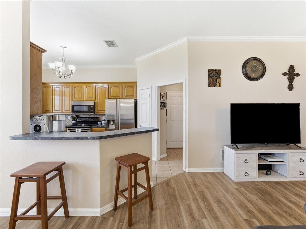10000 Fireside Lane Forney, TX 75126 - Photo 22 of 40 Kitchen featuring a kitchen bar, dark countertops, a peninsula, a chandelier, and stainless steel appliances