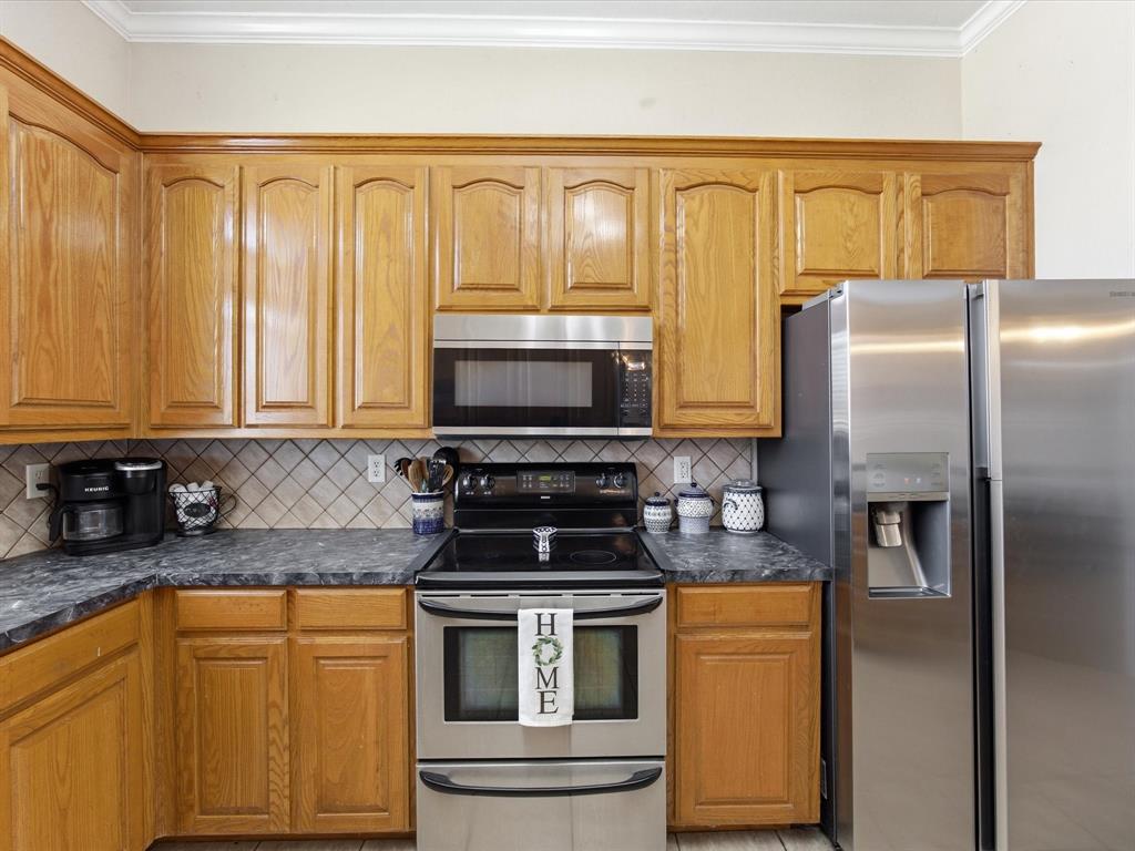 10000 Fireside Lane Forney, TX 75126 - Photo 25 of 40 Kitchen featuring stainless steel appliances, wood finish cabinetry, crown molding, and decorative backsplash