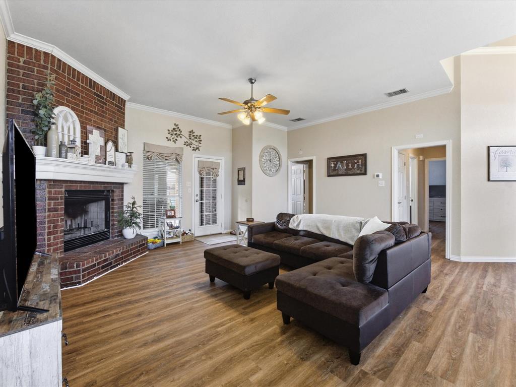 10000 Fireside Lane Forney, TX 75126 - Photo 26 of 40 Living area with wood finished floors, ceiling fan, a brick fireplace, and crown molding