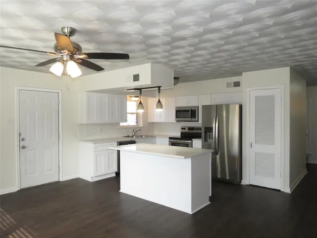 a kitchen with stainless steel appliances a stove a refrigerator a sink dishwasher a refrigerator with a dining table and chairs