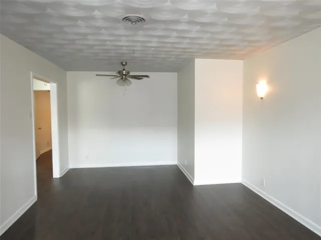 a view of a room with wooden floor and a ceiling fan