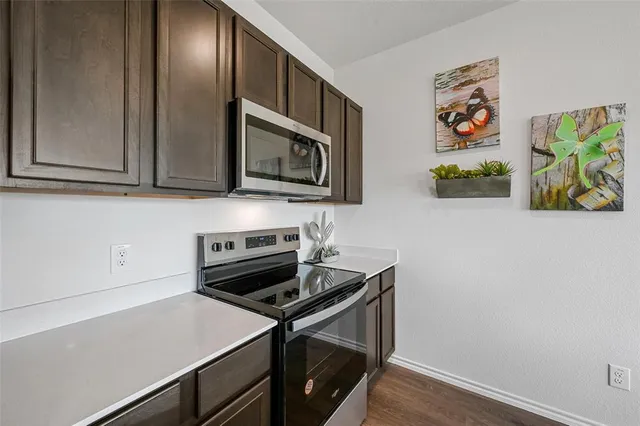 a kitchen with stainless steel appliances a refrigerator a sink a stove a dining table and chairs with wooden floor