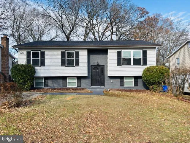 a view of house with a big yard and large trees