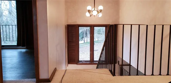 a view of a hallway with wooden floor and a chandelier