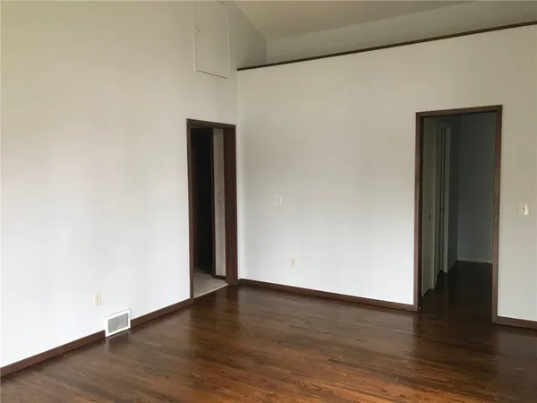 a view of an empty room with wooden floor and closet