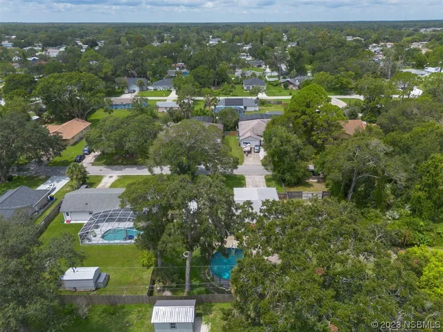 an aerial view of residential houses with outdoor space and trees