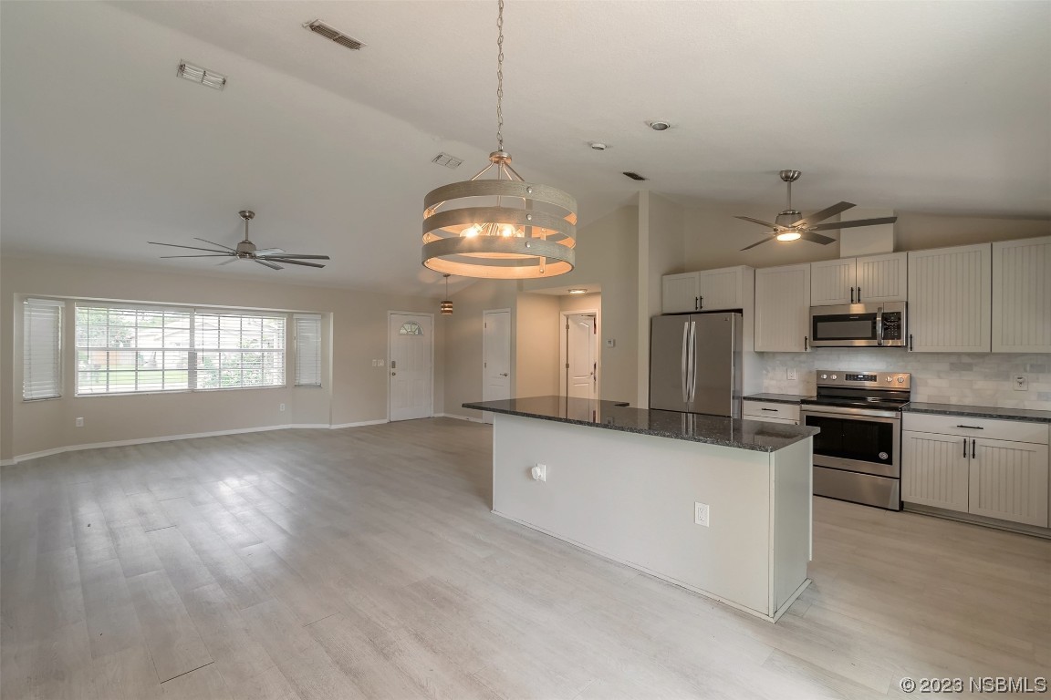2311 Pine Tree Drive Edgewater, FL 32141 - Photo 8 of 32 a large kitchen with granite countertop a stove a sink dishwasher and a refrigerator with wooden floor