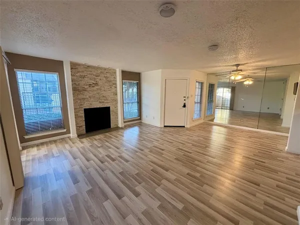 a view of an empty room with wooden floor and a fireplace