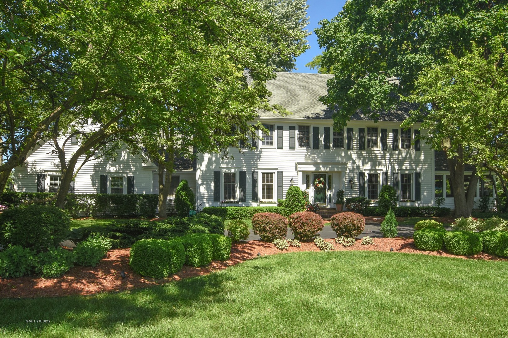 a front view of a house with a garden and trees