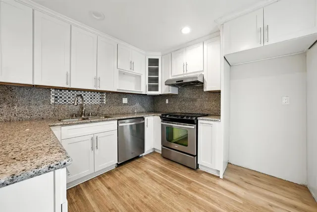 a kitchen with stainless steel appliances granite countertop a sink and a stove