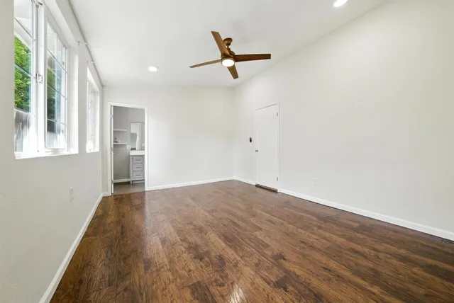 a view of empty room with wooden floor and fan