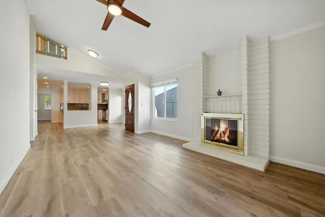 an empty room with wooden floor fire place and windows