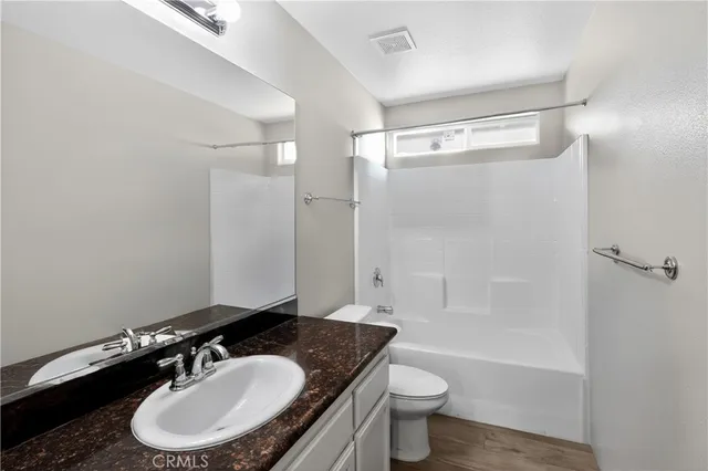 a bathroom with a granite countertop sink toilet a mirror and shower