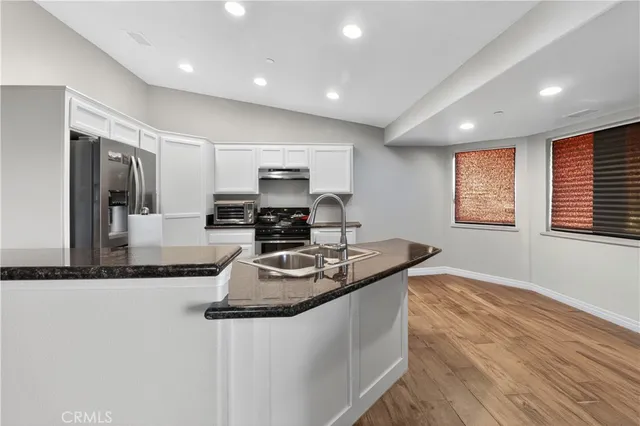 a kitchen with stainless steel appliances granite countertop a sink a stove and a refrigerator