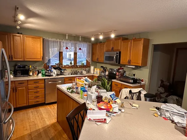a kitchen with stainless steel appliances kitchen island granite countertop a sink dishwasher a refrigerator and cabinets with wooden floor