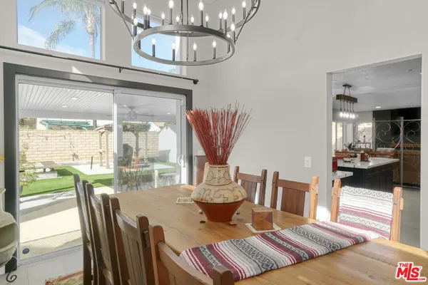 a view of a dining room with furniture a chandelier and kitchen view