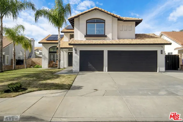 a front view of a house with a yard and palm trees