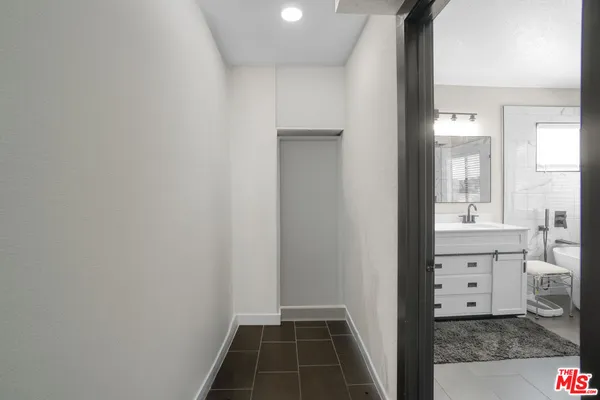 a hallway with a large mirror on dresser and a wooden floor