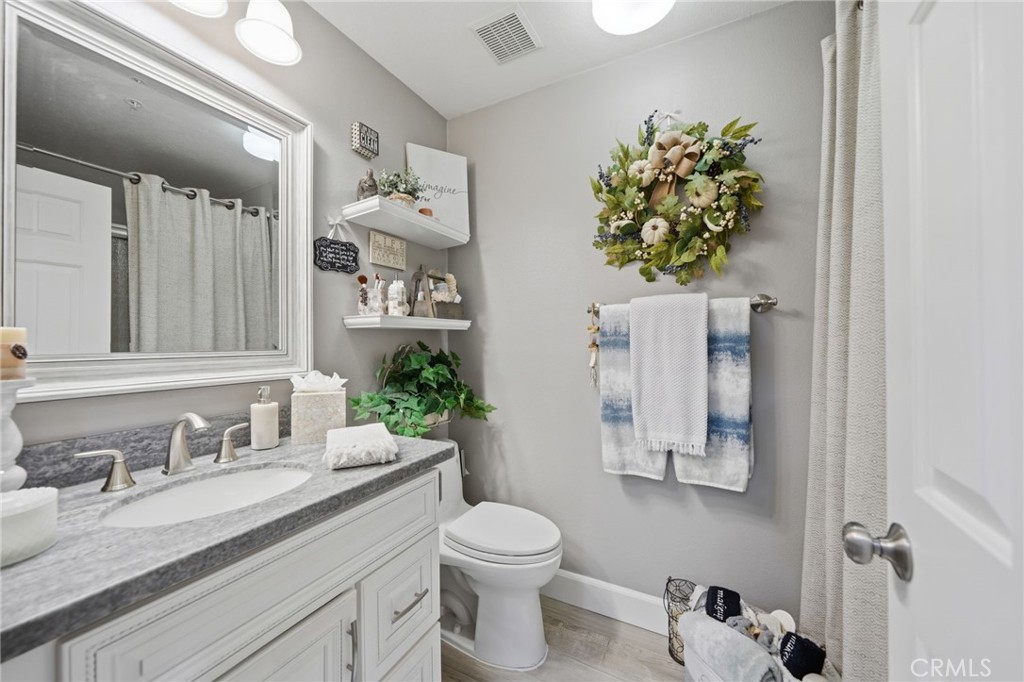 33433 Emerson Way, Unit A Temecula, CA 92592 - Photo 16 of 31 a bathroom with a granite countertop sink a toilet and mirror