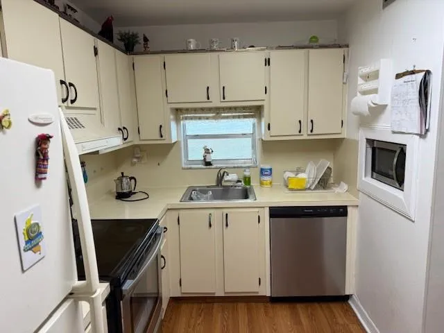 a kitchen with stainless steel appliances a stove a refrigerator a sink a counter space and cabinets