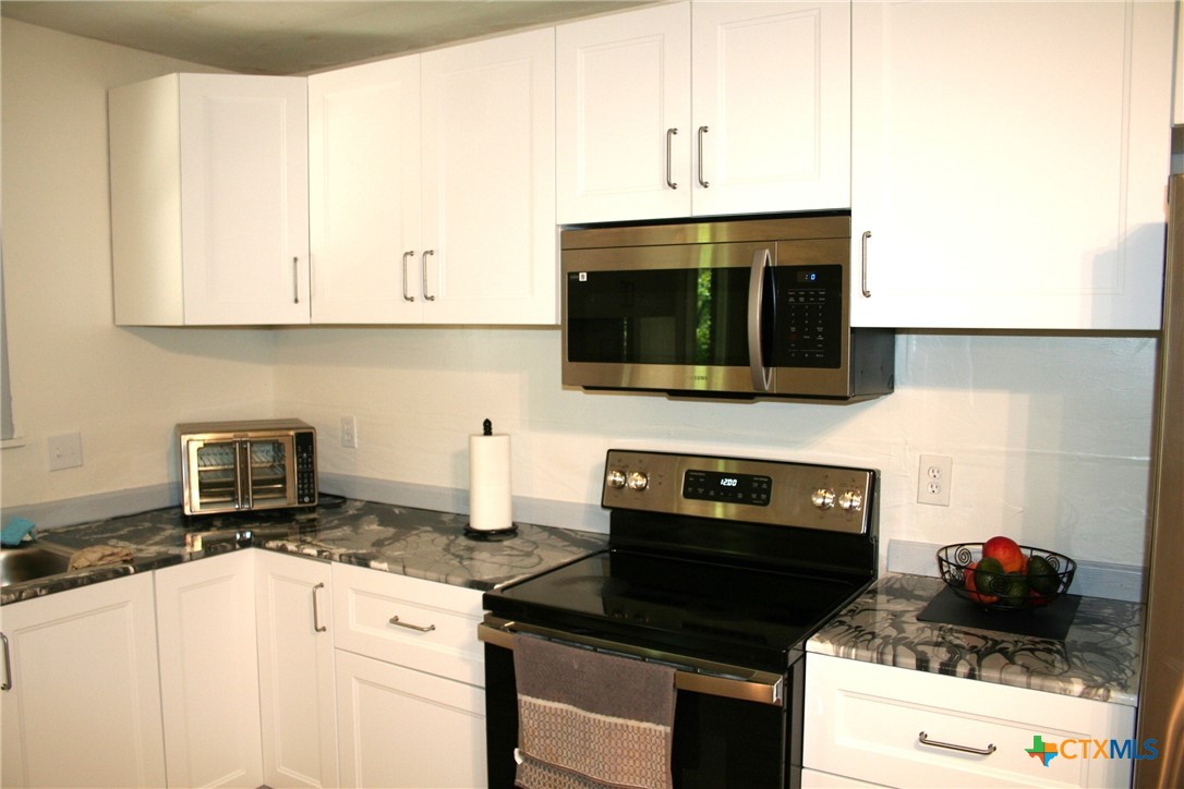 1611 North 10th Street Killeen, TX 76541 - Photo 17 of 31 a kitchen with stainless steel appliances a stove a sink and a microwave
