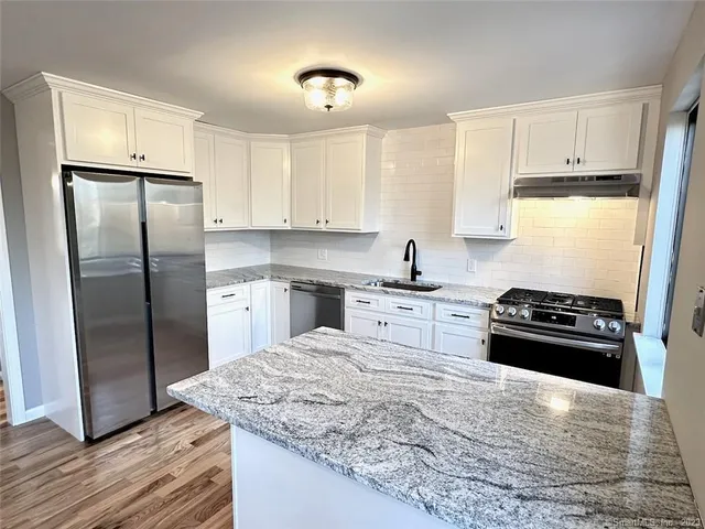 a kitchen with granite countertop a refrigerator stove top oven and sink