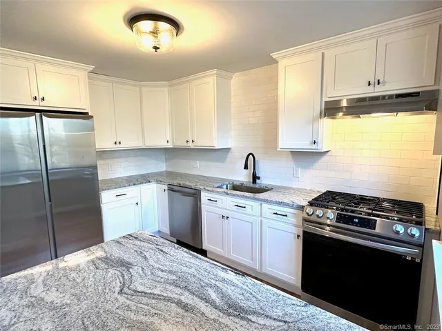 a kitchen with stainless steel appliances granite countertop a stove a sink and a refrigerator