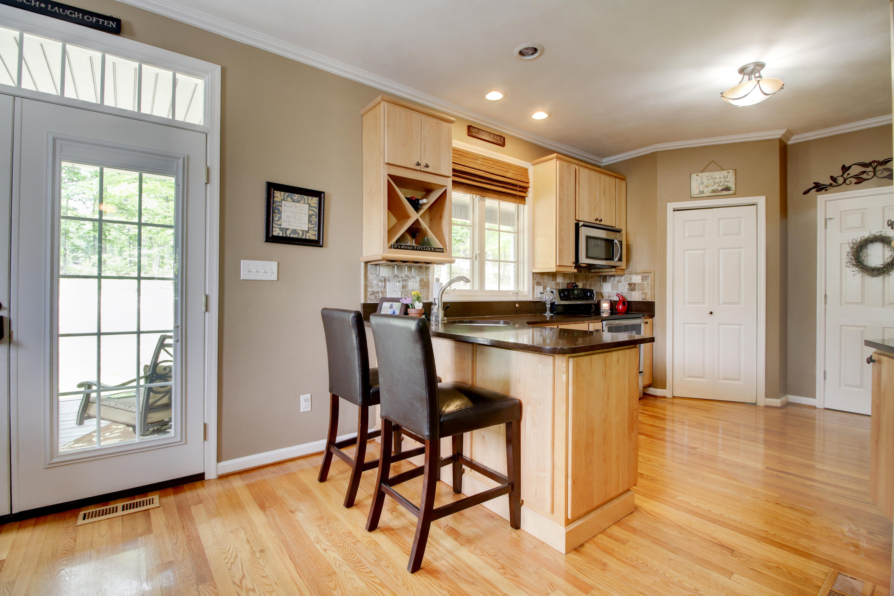 1335 Woodhaven Estates Road Blue Ridge, VA 24064 - Photo 8 of 45 a kitchen with stainless steel appliances granite countertop a stove a refrigerator a microwave a dining table and chairs with wooden floor