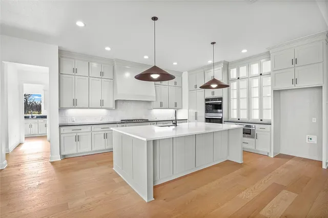 a large kitchen with cabinets wooden floor and stainless steel appliances