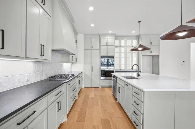 a large kitchen with stainless steel appliances granite countertop a lot of counter space and wooden floors