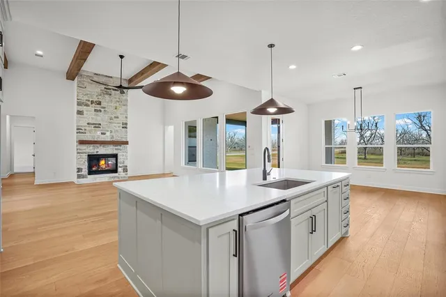 a kitchen with a sink a chandelier stainless steel appliances and cabinets