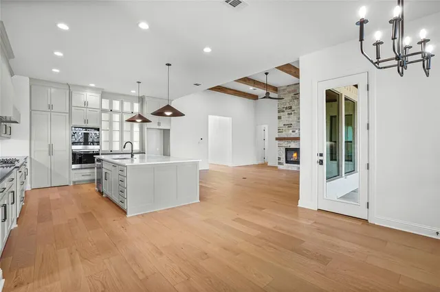 a large kitchen with stainless steel appliances kitchen island a large counter top and wooden floors