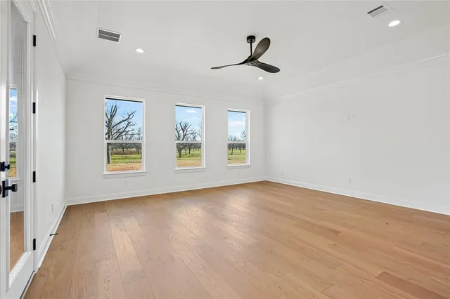 a view of empty room with wooden floor and fan